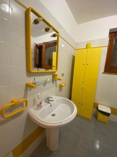 a bathroom with a white sink and a yellow mirror at PM 25 Via Trepene in Castellonorato