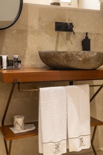 a bathroom with a sink and towels on a shelf at Noto Boutique Hotel in Noto