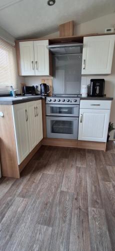 a kitchen with white cabinets and a stainless steel oven at Blue Water Retreat Dawlish Warren Nr Beach in Dawlish Warren