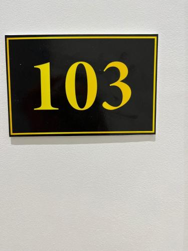 a black and yellow sign on a white wall at Hotel Sisana in Vlorë