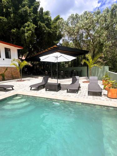 a swimming pool with chairs and an umbrella and a table at Casona San Cayetano Suites & Lofts & Spa by SCE in Guanajuato