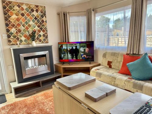 uma sala de estar com um sofá e uma lareira em Deluxe Delta 4-Bedroom Caravan Located at Maryville Caravan Site Uddingston, Glasgow em Uddingston