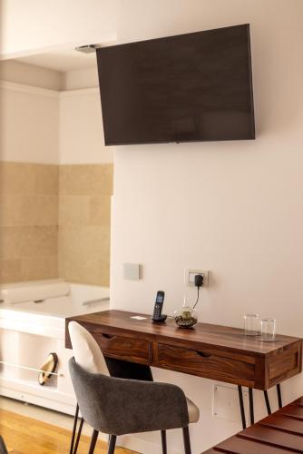 a table with two chairs and a television on a wall at Noto Boutique Hotel in Noto
