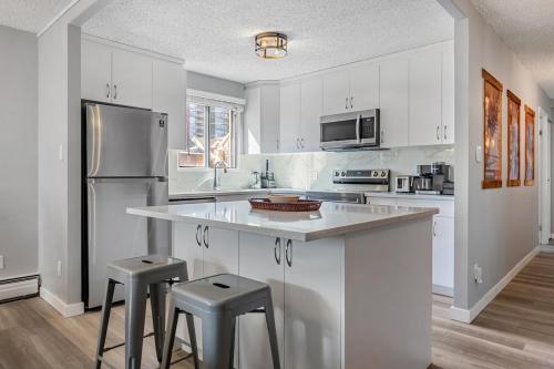 une cuisine avec des armoires blanches et des appareils en acier inoxydable dans l'établissement YYC HiddenGem, à Calgary