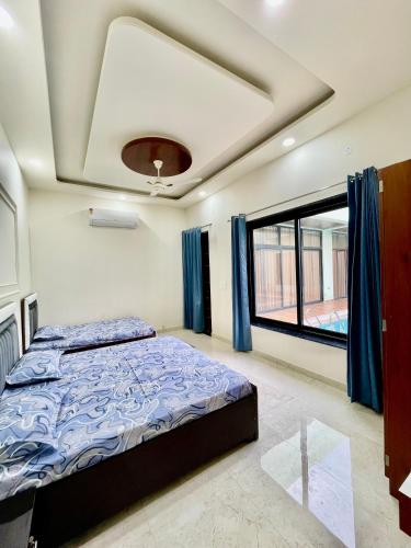 a bedroom with a bed and a large window at ZenRoofs - Pool Farm House in Jaipur