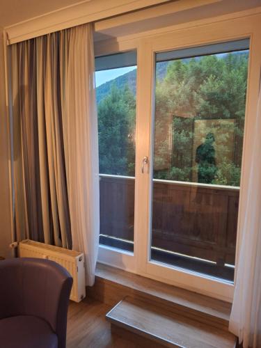 a living room with a large window and a chair at Golfplatz in Bad Ischl