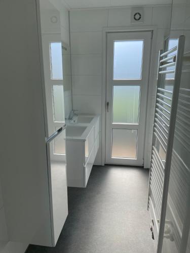 a white bathroom with a sink and a window at Marina Strandbad Chalet Inselperle mit Zaun & AirCo Nr 84 in Olburgen