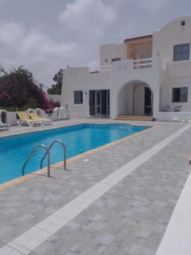 a villa with a swimming pool in front of a house at Villa Sandrella Tazdaine in Temlale