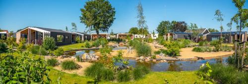 a garden with a pond and some houses at Marina Strandbad Chalet Inselperle mit Zaun & AirCo Nr 84 in Olburgen