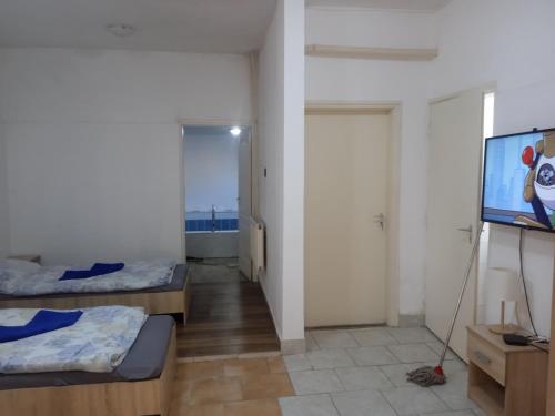 a room with two beds and a flat screen tv at Szilasi Vendégház Apartman2 in Tüskevár