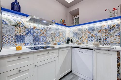 a kitchen with white cabinets and blue and white tiles at LuxurySistersHouse 2 min Colosseum in Rome