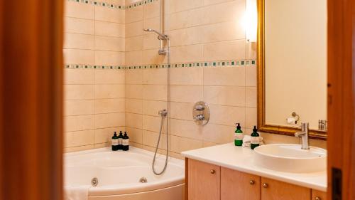 a bathroom with a shower and a tub and a sink at Hotel Rangá in Hella