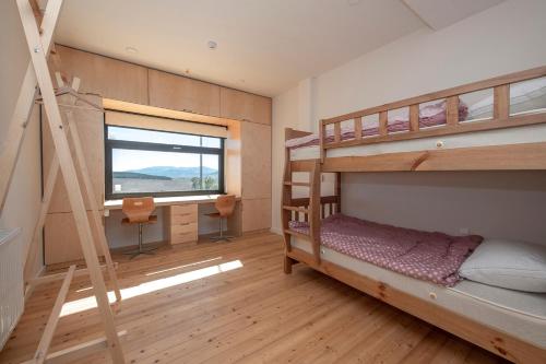a bedroom with bunk beds with a desk and a window at Swiss Agricultural School Caucasus in Sarkinetʼi