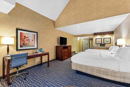 a hotel room with two beds and a desk and a television at Radisson Hotel Salt Lake City Airport in Salt Lake City