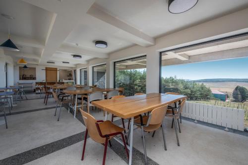 a dining room with tables and chairs and large windows at Swiss Agricultural School Caucasus in Sarkinetʼi
