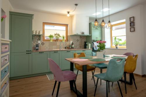 a kitchen with green cabinets and a table and chairs at Apartments Šlosarjeva Hiša Nature & Tradition in Preddvor