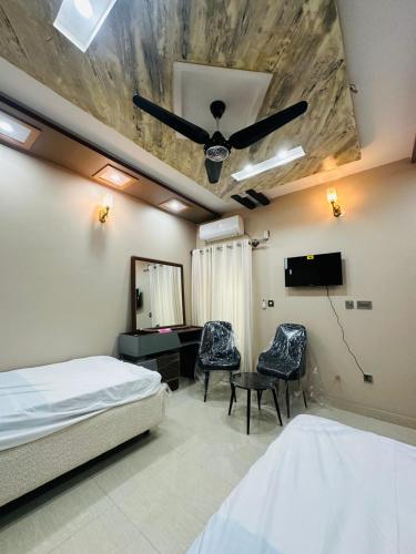 a bedroom with a bed and two chairs and a television at Tabbis Guest House in Islamabad
