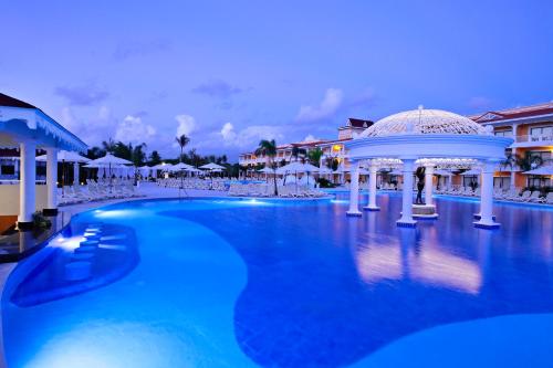 a swimming pool with a blue chair and blue umbrellas at Bahia Principe Grand Aquamarine - All Inclusive in Punta Cana