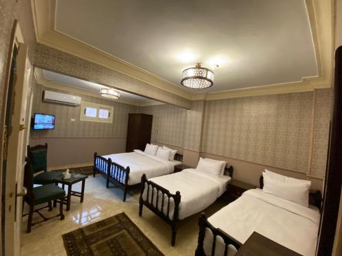 ein Hotelzimmer mit drei Betten und einem Fernseher in der Unterkunft ALRashedy Hotel Powered by Boutique in Kairo