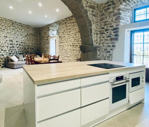 cocina con armarios blancos y pared de piedra en Le Bastion, 15 guests, 5 suites, 5 baths, AC, en Pouzols-Minervois