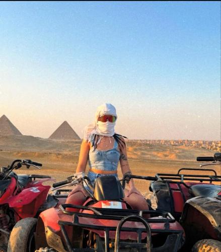 a woman riding a quad bike in front of the pyramids at ayla pyramids inn in Nazlet el-Sîsi