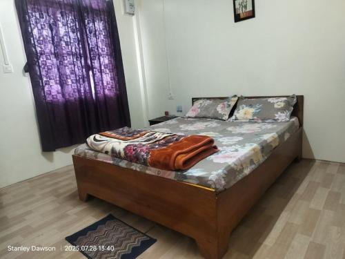 een klein bed in een kamer met een paars raam bij Ado Homestay in Shillong