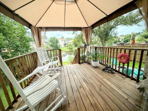 two chairs on a deck with an umbrella at Savannah Lakefront Retreat near Tybee Beach with King Bed and Free Parking in Savannah