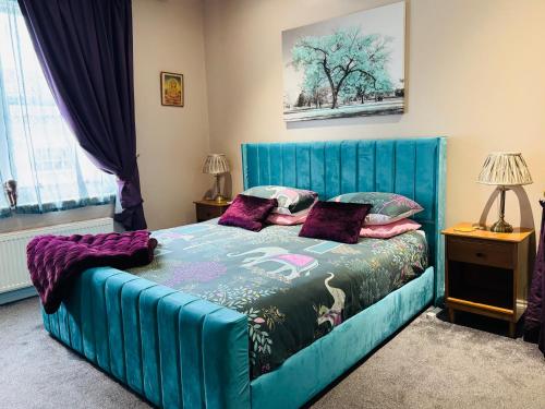 a bedroom with a blue bed with purple pillows at Super King, Close to Beach, Shops, Train, Shared Bathroom in St. Leonards
