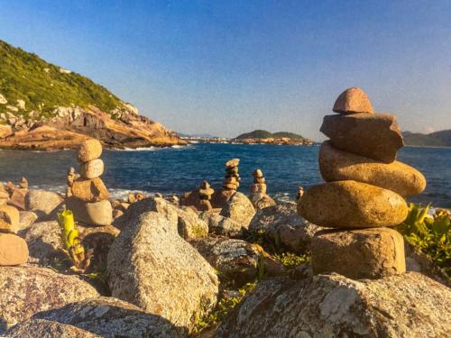 a stack of rocks on the shore of the water at Hotel Heinz in Palhoça