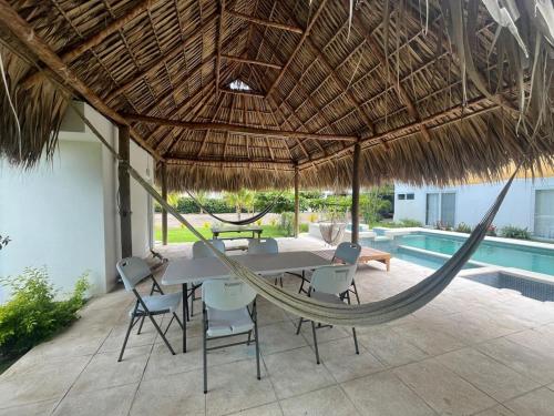 a patio with a table and chairs and a hammock at Villa Almendro - 4 habitaciones in Iztapa