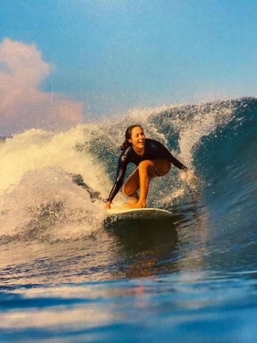 a woman riding a wave on a surfboard in the ocean at Hotel Heinz in Palhoça