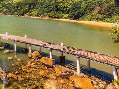 a wooden bridge over the water next to a beach at Hotel Heinz in Palhoça