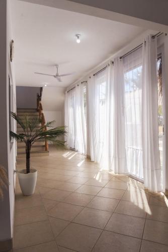 a living room with white curtains and a potted plant at Villa Almendro - 4 habitaciones in Iztapa