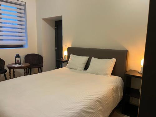 a bedroom with a white bed with two pillows at Ecole Buissonnière in Vielsalm