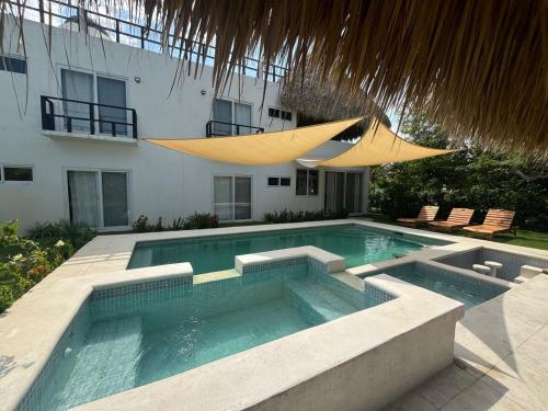 a swimming pool in front of a building with a umbrella at Villa Almendro - 4 habitaciones in Iztapa