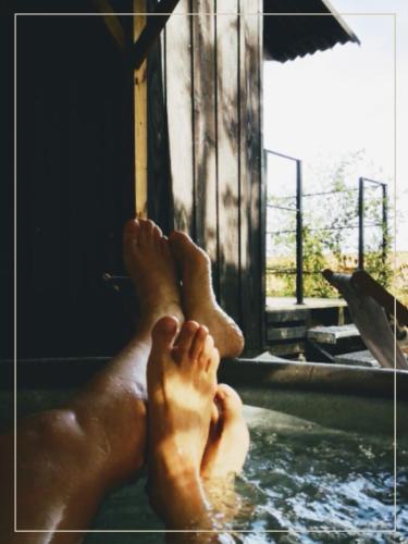 a person laying in a pool with their feet in the water at La Pause En Soi in Ponlat-Taillebourg