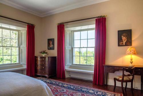 a bedroom with red curtains and a bed and a desk at Marble Hill House in Marble Hill