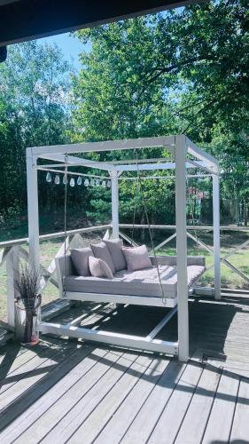 a porch swing with pillows on a deck at Na Skraju Puszczy in Cieciory