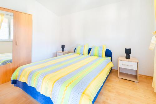 a bedroom with a bed with a colorful striped bedspread at Apartment Vir Croatia in Vir