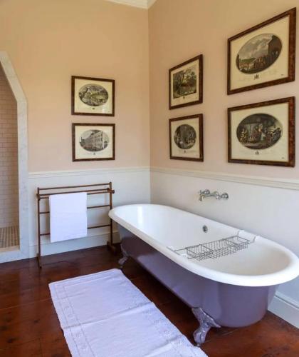 a large bath tub in a bathroom with pictures on the wall at Marble Hill House in Marble Hill