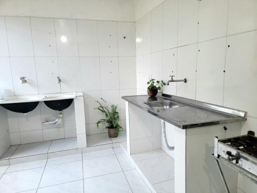 a white kitchen with a sink and a counter at Casa na Praça de Serra Grande in Uruçuca