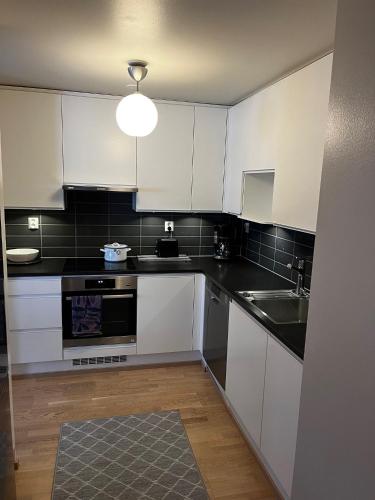 a kitchen with white cabinets and a sink at Great two bedrooms apartment with a sea view from the balcony close Helsinki center in Helsinki
