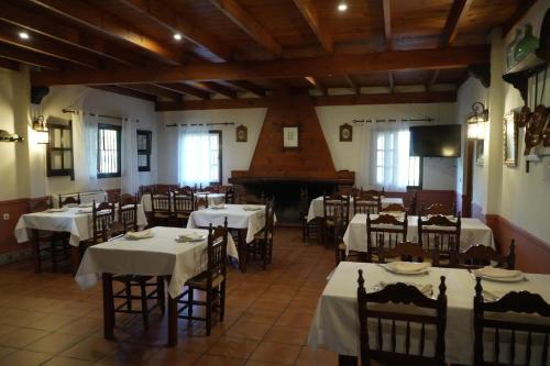 a dining room with tables and a grand piano at Posada el Camino Almonaster in Almonaster la Real
