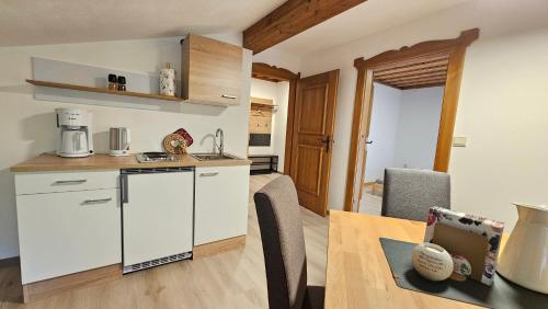 Una cocina con gabinetes blancos y una mesa de madera. en Pfleger Ranch am Schönegg Gut, en Bischofshofen