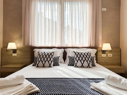 a bedroom with a bed with pillows and a window at Bel Ami Suita Hotel in Vlorë