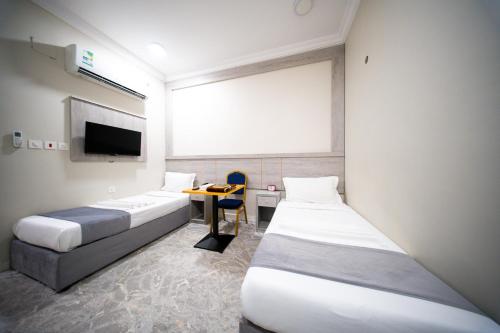 a room with two beds and a desk and a tv at فندق ريحانة المكان من اورفانا in Makkah