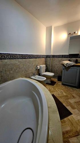 a bathroom with a large tub and two toilets at Votre Villa Soleil et Chaleureuse in Marrakesh
