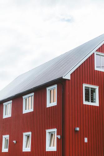 a red barn with white windows on the side of it at Skata Hotel Henningsvær in Henningsvær