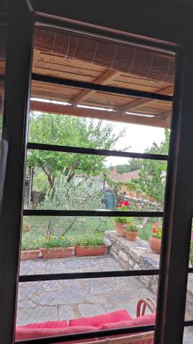 a window view of a patio with potted plants at Μονόχωρος με αυλή in Vrasná