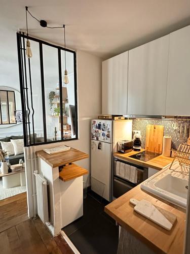 une cuisine avec un réfrigérateur blanc et un comptoir dans l'établissement Appartement proche Montmartre, à Paris
